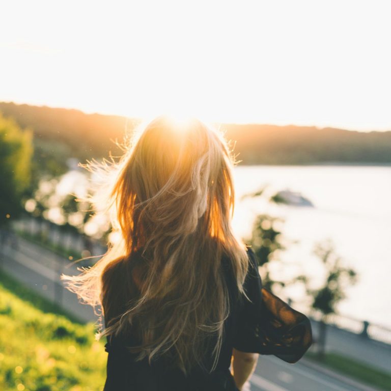 woman sitting on hill looking out on lake
